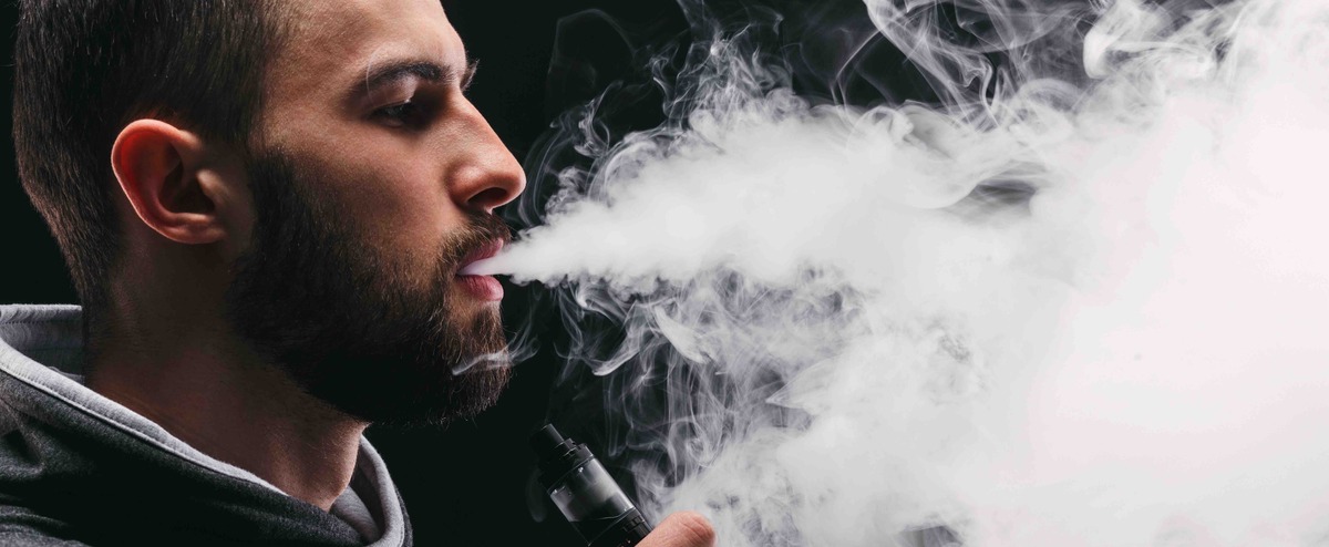 Man with vaping mod exhaling steam