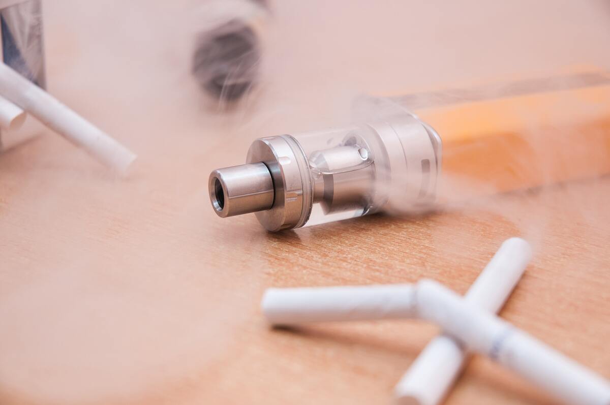 A broken cigarette on a background of the electronic cigarette