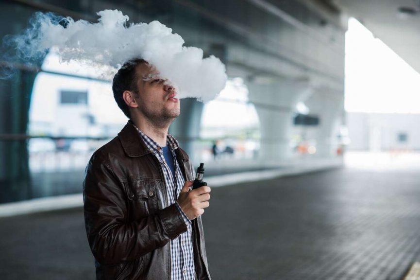 Man vaping in profile against airport terminal background