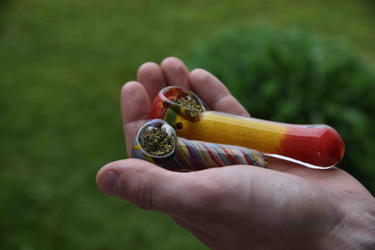 arijuana in two colorful glass pipes in hand